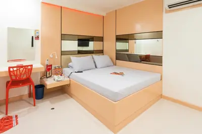 a bedroom with a bed and a red chair at Hotel Sogo Guadalupe in Manila