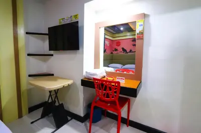 a red chair in a room with a mirror at Hotel Sogo Makati Avenue in Manila