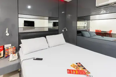 a bedroom with a white bed and a kitchen at Hotel Sogo Cainta in Manila