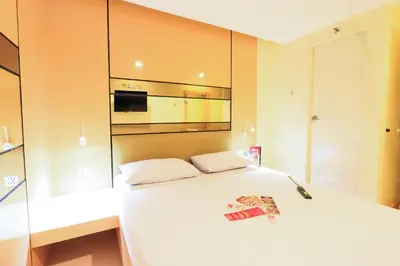 a bedroom with a large white bed with a microwave at Hotel Sogo Alabang Rotonda in Manila
