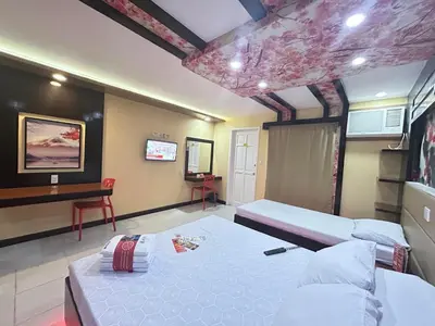 a bedroom with two beds and a desk in it at Hotel Sogo Molino in Cavite