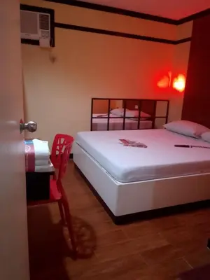 a bedroom with a white bed and a red light at Hotel Sogo San Pedro in San Pedro