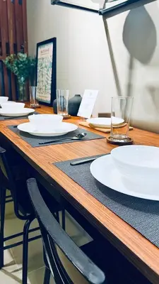 a wooden table with white plates and glasses on it at WinTer Home Stay at S Residences Near Mall of Asia in Manila