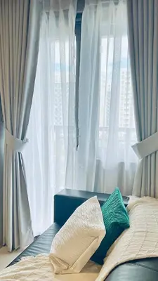 a bed with two pillows sitting in front of a window at WinTer Home Stay at S Residences Near Mall of Asia in Manila