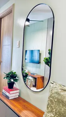 a mirror on a wall above a table with a chair at WinTer Home Stay at S Residences Near Mall of Asia in Manila