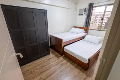 a small room with two beds and a window at 2BR Fully Air-Conditioned Staycation PLUS Free Parking in Manila