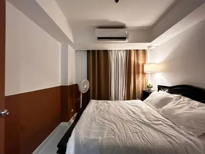 a bedroom with a white bed and a window at Caroshiro Staycation Azure Uban Resort in Manila