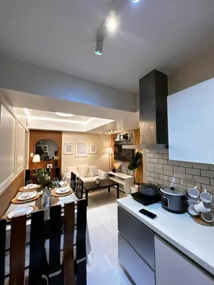 a kitchen and living room with a table and a couch at Caroshiro Staycation Azure Uban Resort in Manila