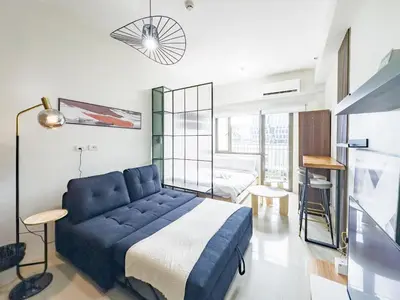 a living room with a blue couch and a bedroom at GemstoneBR in SMDC Shore Residences in Manila