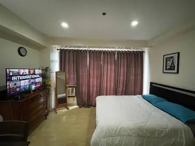 a bedroom with a bed and a flat screen tv at SOHO Condotel EDSA Shaw near SM Megamall FREE Pool Access in Manila