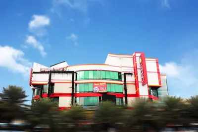 a red and white building with trees in front of it at Hotel Sogo Edsa Taft in Manila