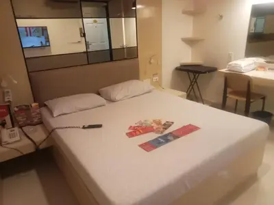 a white bed with a remote control on top of it at Hotel Sogo Pasay Wood Street in Manila