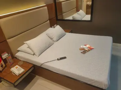 a bed with a remote control and a mirror at Hotel Sogo Macapagal in Manila