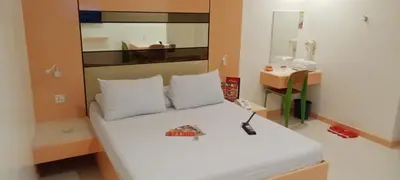 a bedroom with a bed with white pillows and a mirror at Hotel Sogo Buendia in Manila