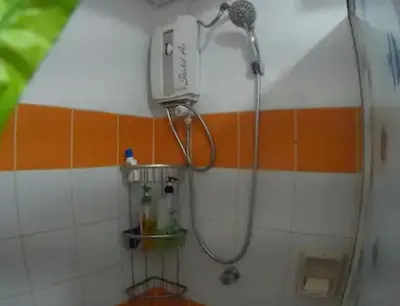 a shower in a bathroom with an orange and white wall at Rsquared Condo in Manila