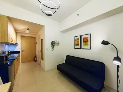 a living room with a black couch in a kitchen at 1BR Condotel with Balcony at SM Light Residences #LT05 in Manila
