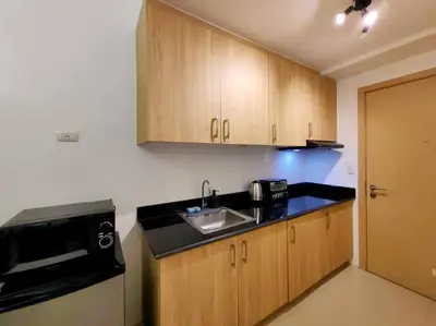 a kitchen with wooden cabinets and a black counter top at 1BR Condotel with Balcony at SM Light Residences #LT05 in Manila