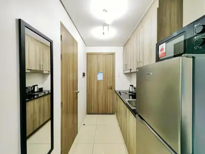 a kitchen with wooden cabinets and a stainless steel refrigerator at 1BR Condotel with Balcony at SM Light Residences #LT05 in Manila