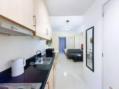 a kitchen with a sink and a living room at 1BR Condotel with Balcony at SM Light Residences #LT06 in Manila