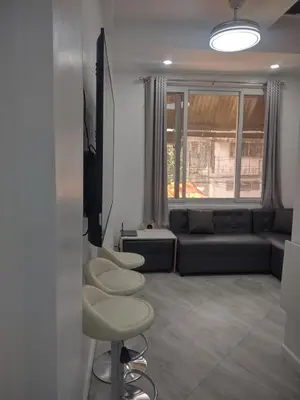 a living room with a couch and two stools at Bellas Apartment u2 in Manila