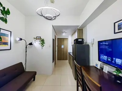 a living room with a couch and a large screen tv at 1BR Condotel with Balcony at FAME Residences #FM09 in Manila