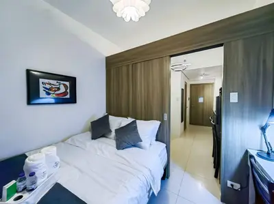 a hotel room with a white bed and a desk at 1BR Condotel with Balcony at FAME Residences #FM09 in Manila