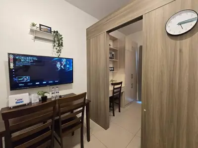 a living room with a large clock on the wall at 1BR Condotel with Balcony at FAME Residences #FM13 in Manila