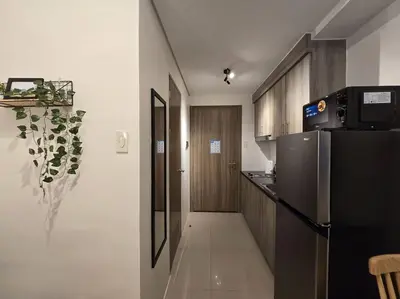 a kitchen with a black refrigerator and a hallway at 1BR Condotel with Balcony at FAME Residences #FM14 in Manila