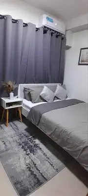 a bedroom with a bed with blue curtains and a table at The Q's Place in Manila