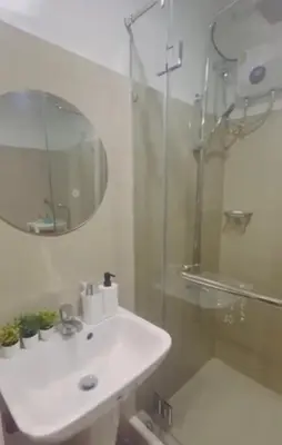 a white bathroom with a sink and a shower at The Q's Place in Manila