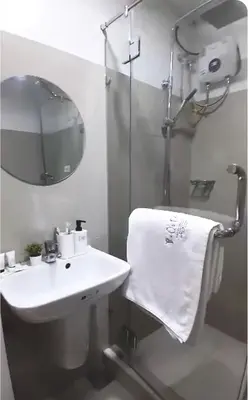 a bathroom with a sink and a shower with a towel at The Q's Place in Manila