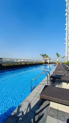 a swimming pool with benches and a bridge in the background at SMDC Coast Residences in Manila