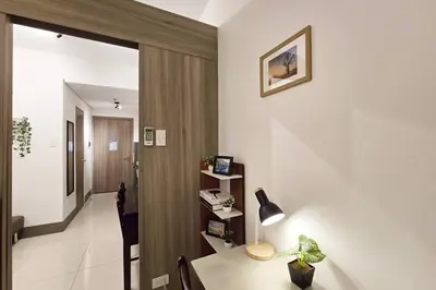 a room with a desk with a lamp and a hallway at 1BR Condotel with Balcony at FAME Residences #FM21 in Manila
