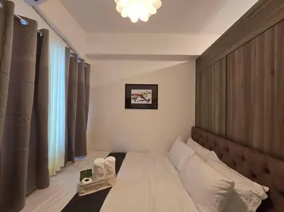 a bedroom with a large bed with a wooden headboard at 1BR Condotel with Balcony at FAME Residences #FM21 in Manila
