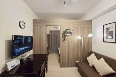 a living room with a couch and a television at 1BR Condotel with Balcony at FAME Residences #FM21 in Manila