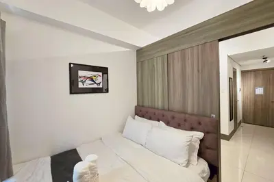 a bedroom with a bed with white sheets and pillows at 1BR Condotel with Balcony at FAME Residences #FM21 in Manila