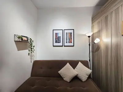 a living room with a brown couch and two pictures at 1BR Condotel with Balcony at FAME Residences #FM22 in Manila