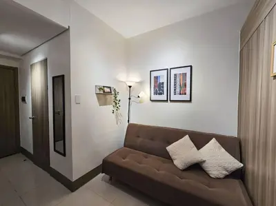 a living room with a brown couch in a room at 1BR Condotel with Balcony at FAME Residences #FM22 in Manila