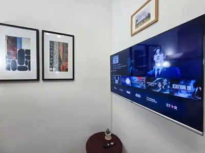 a flat screen tv hanging on a wall with pictures at 1BR Condotel with Balcony at FAME Residences #FM23 in Manila