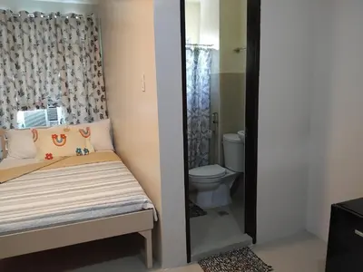a small bedroom with a bed and a toilet at AGB Anchorage Inn in Manila