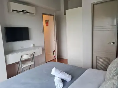 a bedroom with a bed with a television and a chair at Big 2BR near Burgos Circle, Highstreet, St Lukes - B Parklane T1 in Manila