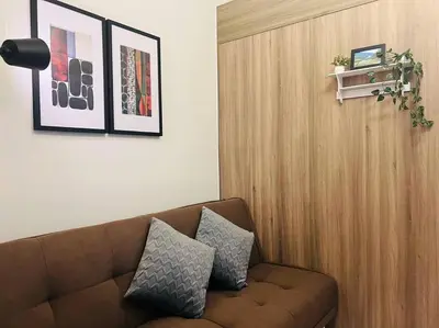 a living room with a brown couch with two pillows at 1BR Condotel with Balcony at FAME Residences #FM27 in Manila
