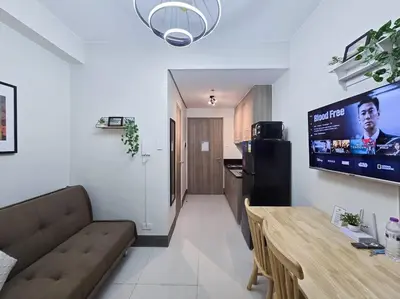 a living room with a couch and a television on the wall at 1BR Condotel with Balcony at FAME Residences #FM29 in Manila