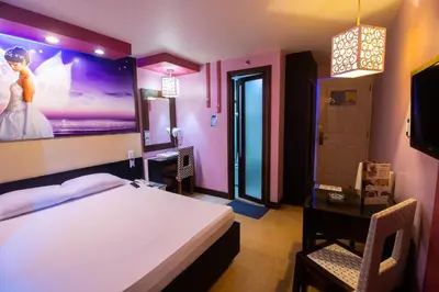 a bedroom with a bed and a desk and a tv at Hotel Dreamworld Las Pinas in Manila