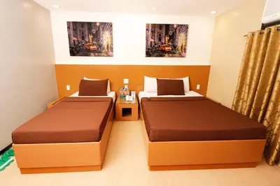 a hotel room with two beds and a table at Eurotel Las Pinas in Manila