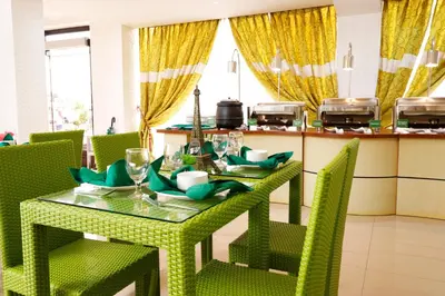 a dining room with a green table and chairs at Eurotel Las Pinas in Manila