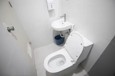 a white bathroom with a toilet and a sink at Astrotel Calamba in Calamba