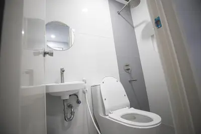 a white bathroom with a toilet and a sink at Astrotel Calamba in Calamba
