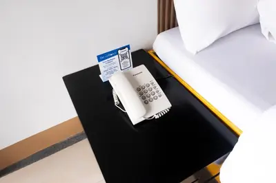 a phone sitting on a table next to a bed at Hotel Dreamworld Araneta Cubao in Manila