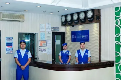 three people in blue uniforms standing in front of a counter at Hotel Dreamworld Araneta Cubao in Manila
